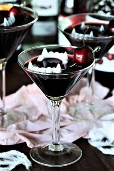 two martinis with cherries and marshmallows in them on a table