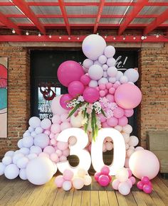 the balloon arch is decorated with pink, white and grey balloons that spell out the number 30