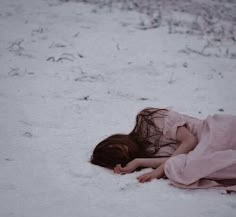 a woman laying in the snow with her head down