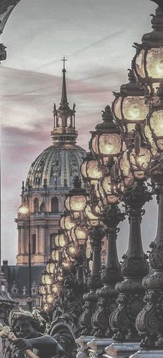 an image of a city street with many lamps and buildings in the background at dusk