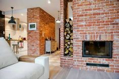 a living room filled with furniture next to a fire place in a brick wall fireplace