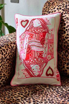 a red and white pillow sitting on top of a leopard print chair