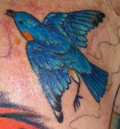 a close up of a person's chest with a blue bird on it