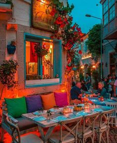 an outdoor dining area with tables, chairs and potted plants on the outside wall