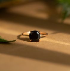 a black diamond ring sitting on top of a wooden table next to a green plant