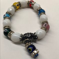 This Beautiful Brand New Multi Color Evil Eye And White Glass Beaded Stretch Glass Bracelet With Cubic Zirconia. It Is Made Of Top Quality Materials And Authentic Approx Measurements 8" Hanging Evil Eye Charm Promotes Good Luck, Healing And Defends Against Negative Energy White Crystal Bracelet With Round Beads, Adjustable White Round Evil Eye Bracelet, White Evil Eye Bracelet With Round Beads, White Beaded Round Evil Eye Bracelet, White Round Beaded Evil Eye Bracelet, White Evil Eye Beaded Bracelets, White Stretch Bracelet With 8mm Beads, White Crystal Bracelet With Colorful Round Beads, White Spiritual Bracelets With Colorful Beads