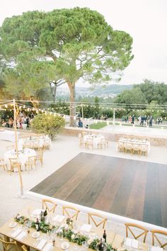 an outdoor venue with tables and chairs set up for a wedding reception under a tree