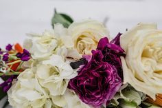 a bouquet of white and purple flowers sitting on top of a table next to each other