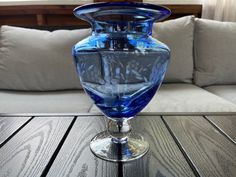 a blue glass vase sitting on top of a wooden table next to a white couch