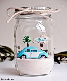 a glass jar filled with sand and a blue car