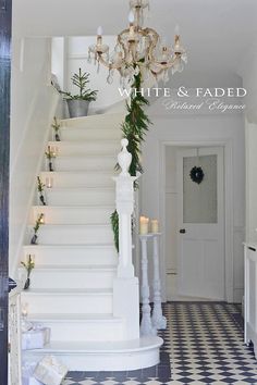 a white staircase with candles and greenery on the steps leading up to an entry door