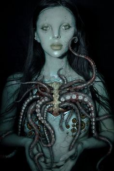 an image of a woman with octopus tentacles on her chest and face, in the dark