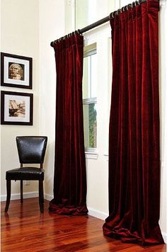 a chair sitting in front of a window with red curtains hanging on it's side