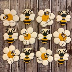 decorated cookies in the shape of flowers and bees on a wooden table with wood planks