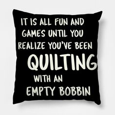 a black pillow with the words quilting and empty bobbin printed in white on it