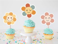 three cupcakes with blue frosting and flowers on top