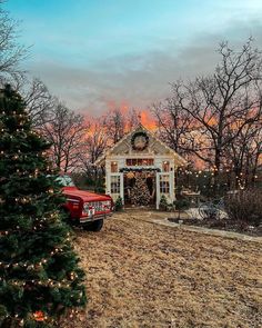 a red truck is parked in front of a small house with christmas lights on it