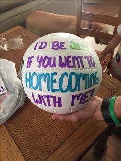 a person holding a white ball with writing on it that says i'd be if you went to home coming with me