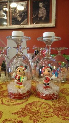 three wine glasses sitting on top of a table covered in snow and mickey mouse figurines