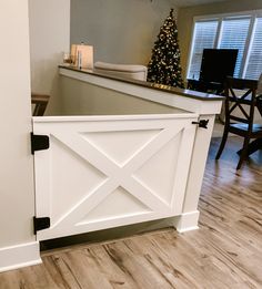 a white barn door is opened to reveal a living room with a christmas tree in the background