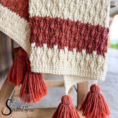 a crocheted blanket with tassels hanging from the back of a chair