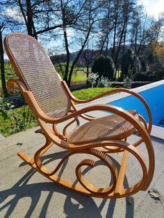 a rocking chair sitting on top of a patio next to a swimming pool