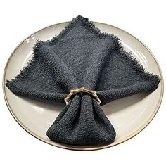 a white plate topped with a napkin on top of a blue and white plate covered in black cloth