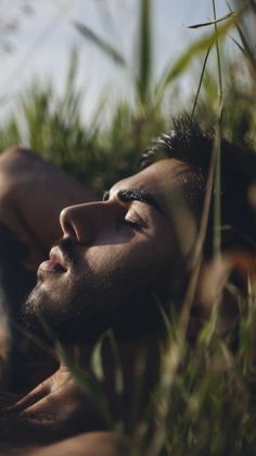 a man laying in the grass with his eyes closed and head tilted to the side