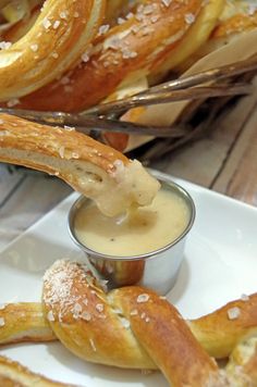 bread sticks being dipped with dipping sauce on a white plate next to other baked goods