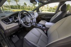 the interior of a vehicle with grey leather seats and steering wheel, palm trees in the background