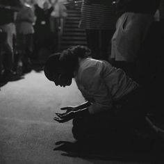 a black and white photo of a woman kneeling down on the floor with her hands in her pockets