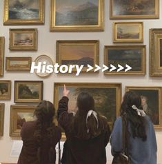 three girls are looking at paintings on the wall and pointing to them with their hands