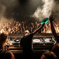 a dj holding up a frisbee in front of a crowd