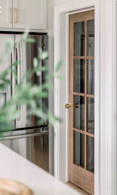 an open door leading to a kitchen with white cabinets and stainless steel refrigerator freezer