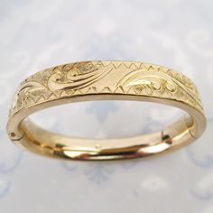 "A wonderful engraved design tops this vintage 10k gold filled oval bangle bracelet. The bracelet has a dense weight and thick heavy gold finish. Gold swirls and a circular pattern flows across the bracelet with the small central surface plain and shiny (meant for a monogram). The back of the bracelet is also plain. The 7/16 inch wide bracelet has an oval curvy shape. The sturdy form is nice and smooth with no major dings. The bracelet opens with a tiny push-button and closes securely. The inside is signed \"EJC\" on one side and hallmarked, \"10K Gold Shell (gold filled)\" on the other. The bracelet tested as gold filled and the total inner circumference of the bangle measures approx.  6 5/8 inches. It is in very good vintage condition with expected surface wear as pictured. There is an i Vintage 14k Stamped Gold Bangle Bracelet, Vintage 14k Gold Hallmarked Bangle, Antique Stamped 14k Bangle Bracelet, Vintage 14k Stamped Round Bangle, Antique 14k Gold Bangle Bracelet, Antique Round 14k Gold Bangle, Antique 14k Gold Round Bangle, Vintage 14k Stamped Gold Bangle, Antique 14k Gold Bracelet Engraved