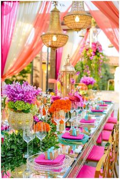 the table is set with pink and orange flowers in vases on top of it