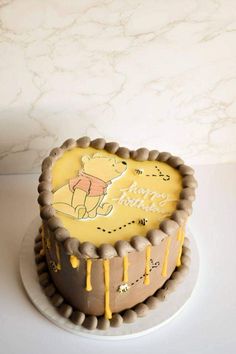 a winnie the pooh birthday cake with yellow icing on it's side