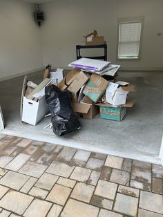 a pile of boxes sitting on top of a floor next to a black trash can