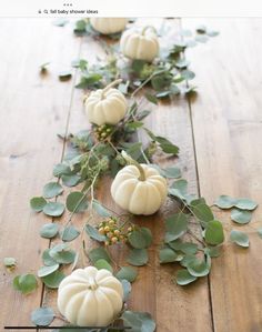 white pumpkins and greenery on a wooden table