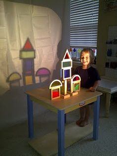 a little boy that is standing in front of a table with some building blocks on it