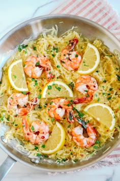 a pan filled with shrimp and lemons on top of a table