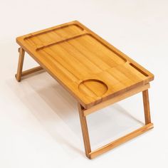 a small wooden tray on top of a folding table with an oval hole in the middle