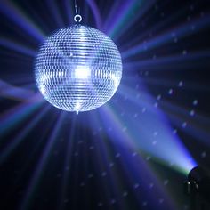 a disco ball hanging from the ceiling in front of bright blue and purple lights with stars