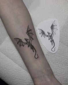 a small dragon tattoo on the left forearm and right arm, with wings spread out