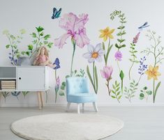 a child's room with flowers and butterflies painted on the wall, along with a blue chair