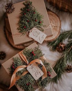 two wrapped presents sitting on top of a white fur covered floor next to pine cones