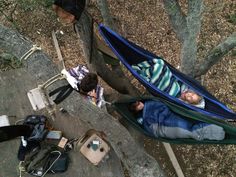 two people laying in a hammock on the ground