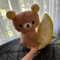 a person holding a teddy bear with a slice of lemon on it's back