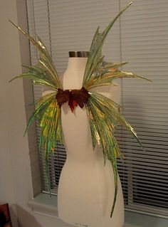 a white vase sitting on top of a table next to a window with blinds behind it