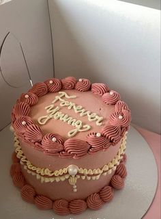 a pink birthday cake sitting on top of a table